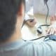 A healthcare professional measures a patients blood pressure with a sphygmomanometer at a desk.