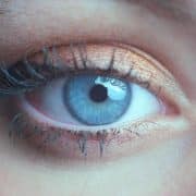 Close-up of a blue eye with long eyelashes and shimmery copper eyeshadow on the eyelid.