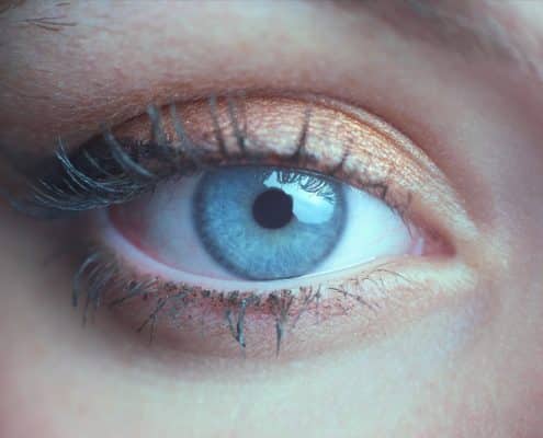 Close-up of a blue eye with long eyelashes and shimmery copper eyeshadow on the eyelid.