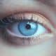 Close-up of a blue eye with long eyelashes and shimmery copper eyeshadow on the eyelid.